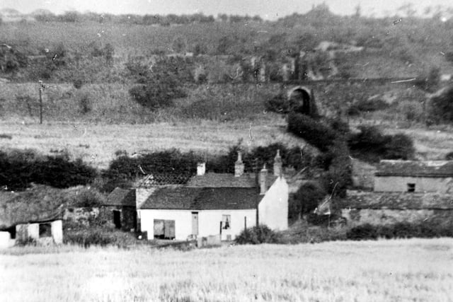 The farm house and barns of Middleton Mill Farm. Surrounded by fields and farm land. In the distance is a railway line.