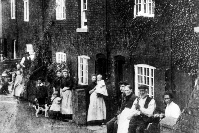 Families posed outside cottages on Low Grange known as 'woo-cud-a-thouwt-it'. Nickname came about from a chance remark made by Queen Victoria on being impressed by the panoramic views as she passed to open Leeds Town Hall in 1858.