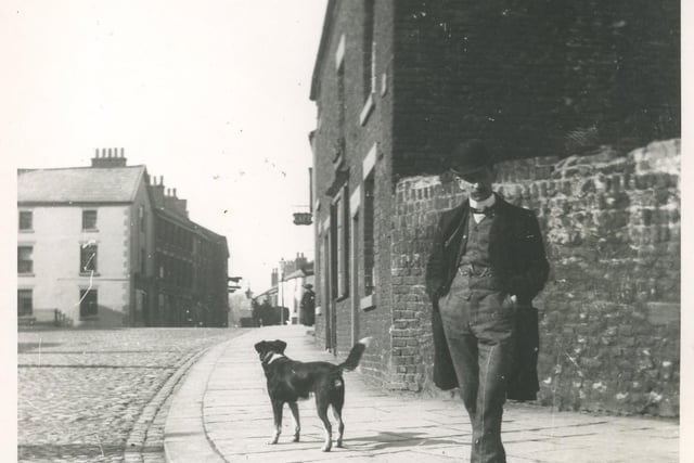 A man and his dog posing for a picture in Queens Square close to the junction with Chapel Street. Beyond is the Bull Hotel with its distinctive sign profile.
