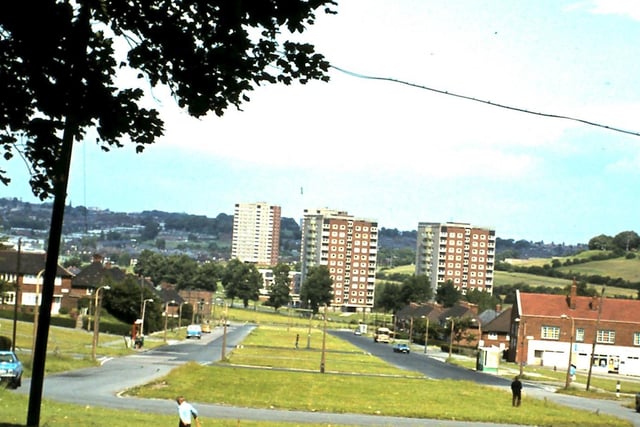Coldcotes Drive. To the right are the Coldcotes Circus shops. In the background are blocks of high-rise flats; nearest the camera are Pembroke Towers, centre, and Pembroke Grange, right, located on Wykebeck Valley Road.