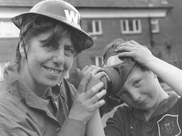 Mavis Crawforth, a community worker at Edgehill Community Centre, helps Mark Reedie with his gas mask.