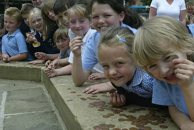 Children from Bailiff Bridge J&I School placed coins around the edge of the memorial monument in 2005.