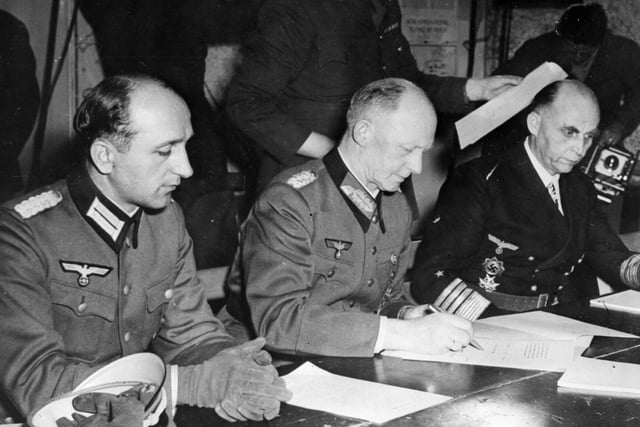 Here, General Alfred Jodl, Hitler's military advisor, controller of German High Command and chief of the Operations Staff (centre), signs the document of surrender, bringing the war to a formal end.