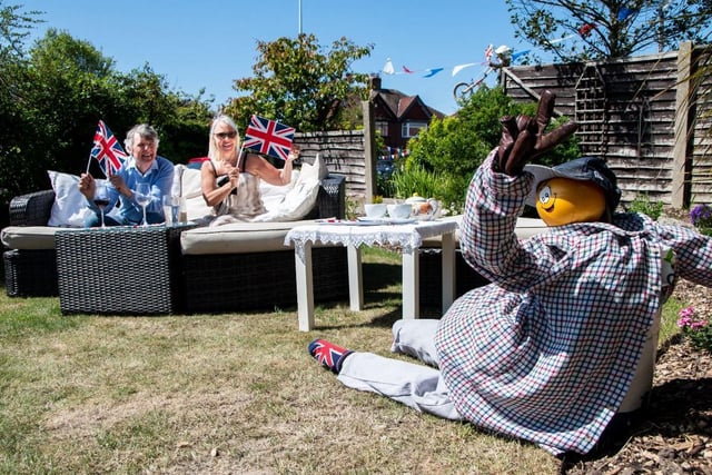 John and Pam Duckworth wave Union Flags whilst their scarecrow gives a V for victory salute at their garden party in Bispham