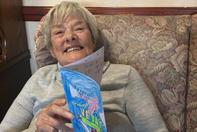 A resident at The Sands care home reading a card on VE Day.