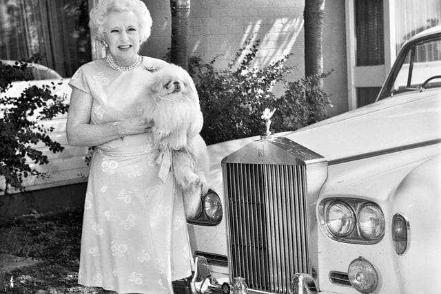 Romantic novelist Barbara Cartland pictured at Almond Brook Restaurant, Standish, where she had called for lunch on her way from London to her holiday home in Scotland on 25th of August 1978. She is holding her pet Peke, Ty-Ty, next to her Rolls Royce.