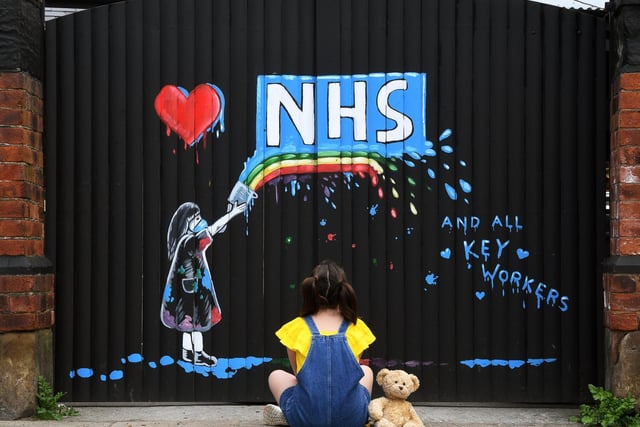 A young girl stops to admire an NHS mural painted on the side of the Hope & Anchor pub in Pontefract, by artist Rachel List.
