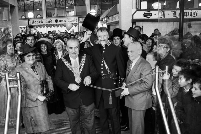 The Mayor of Wigan, Councillor Jimmy Jones, cuts the cord to officially open the new Wigan Market Hall on Thursday 21st of January 1988.  With him are the mayoress, Chief Markets Officer, John Edwards, Council Leader, Bernard Coyle and stall holders and customers.
