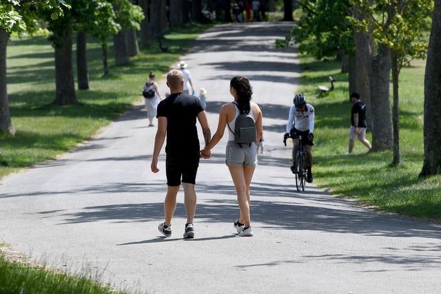 A couple have a summer's walk through the park.
