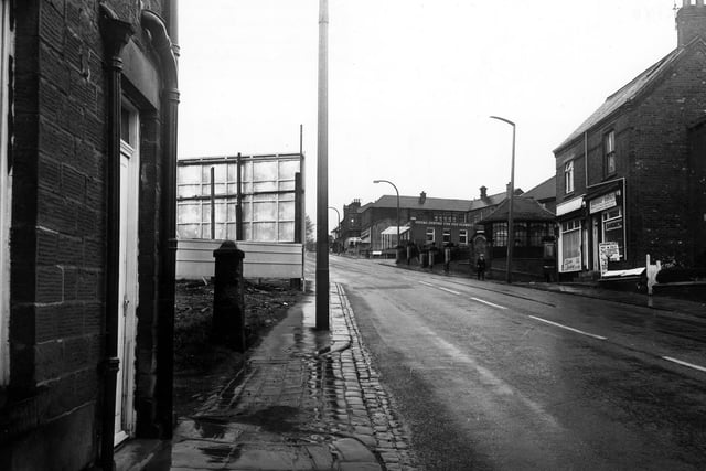 Elland Road with the junction with Old Road on the right, next to Diane Lesley, ladies hairdresser at no.34, with Pioneer Catering at no.32. Beyond Old Road is the war memorial, then the junction with William Street.