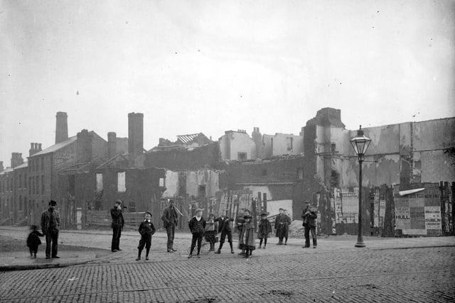 Melbourne Street, from North Street, during demolition of buildings at this end of the street as part of improvements to the area. A line of children in period dress pose for the camera.