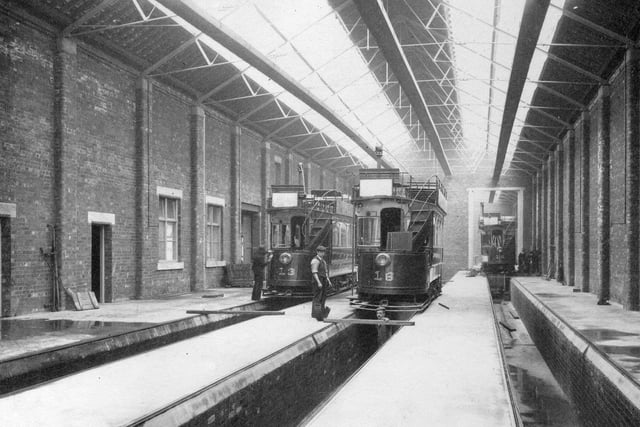 Interior view of Kirkstall Road tram sheds during construction. Workmen and trams can be seen.