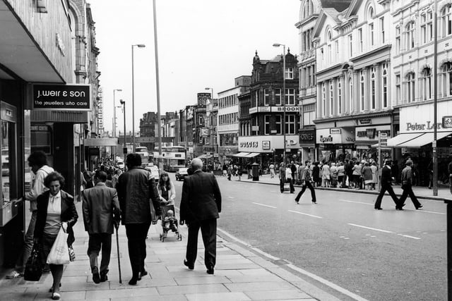 Briggate. On the left J.Weir & Son 'the jeweller's who care' and further down, Debenhams. On the right, Dolcis visible on the corner with Albion Place, then Hornes and Hepworths followed by Army Stores and Peter Lord's far right.