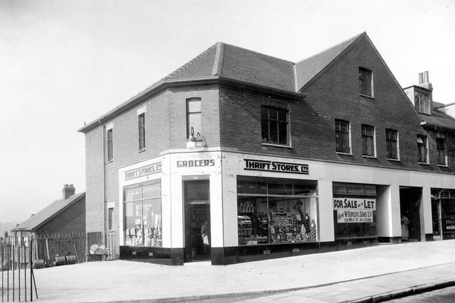 Thrift Stores Ltd on junction of Kirkstall Hill with Burley Wood Lane. Shows double fronted corner shop with large window displays. Garden equipment is stored on pavement outside.