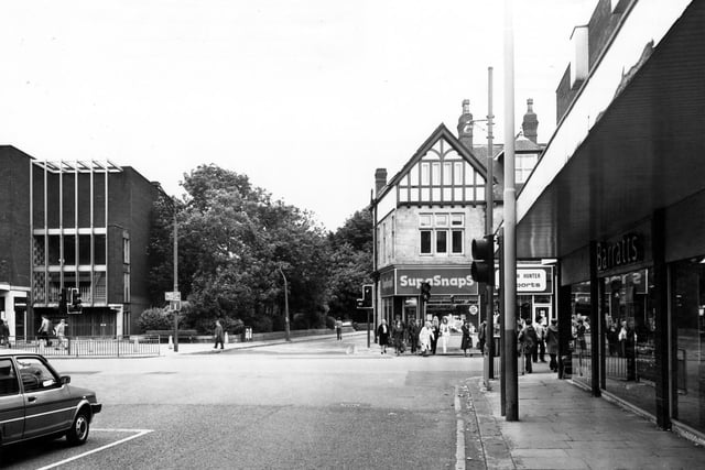 North Lane of the junction with Otley Road and Wood Lane. On the right is Barratts footwear. Shops on Otley Road are SupaSnaps Film Processing and Norman Hunter Sports. On the left is the edge of the Arndale Centre.