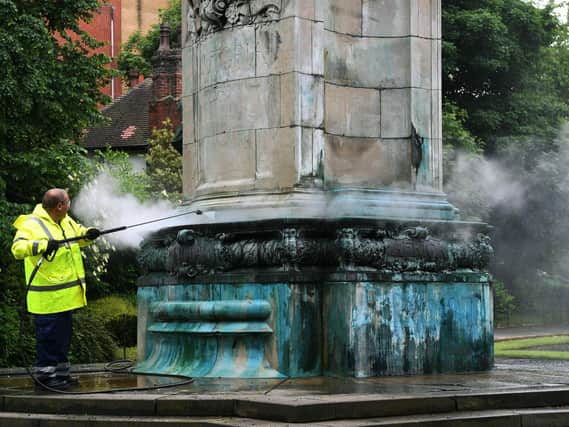 A Leeds City Council worker removes graffiti from the Queen Victoria statue.