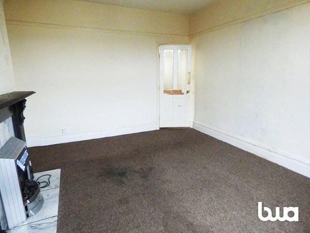 The living room has a fire place and is well lit with natural lighting from the large windows.