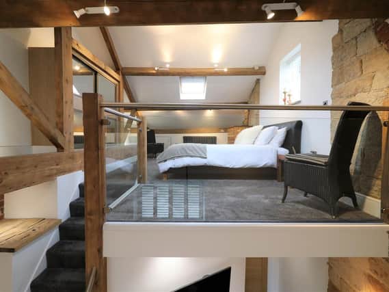 The stunning master bedroom sits on the mezzanine and is an amazing use of architecture using the period beams to create integrated storage space.