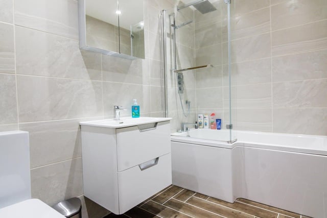 The luxrious family bathroom has a large 'rainfall' shower head and thermostatic controls,  and a 'floating' vanity unit with inset rectangular sink.