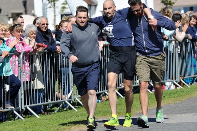 A runner is helped by his mates to cross the line in 2015
