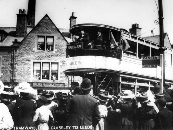 Crowds are gathered to watch the arrival of a tram on the first day of the tramways in Guiseley. The photo is taken on Oxford Road, with the shop of Walter Priestley, butcher, in the background.