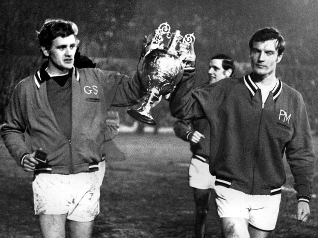 Gary Sprake and Paul Madeley parade he trophy around the Elland Road pitch.