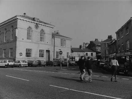 The east side of the Market Place. The Town Hall is on the left. Shops visible from the right include Dacre, Son & Hartley, estate agents, Michael Colbeck gents outfitters, Crockett dry cleaners and News Corner newsagents.