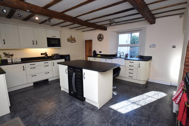 Here are high and low level kitchen units, and a central work island, with granite work surfaces. There is an integrated washing machine, dishwasher and wine cooler, with space for a freestanding gas and electric range cooker.