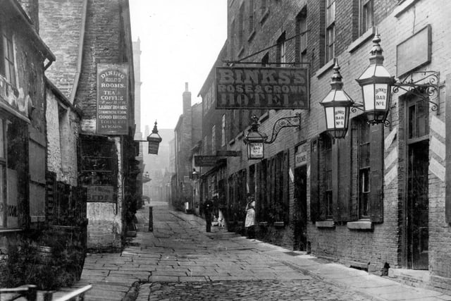 Rose and Crown Yard, now the Queen's Arcade. Image shows Rose and Crown Hotel, lighted signs for Bink's Bars no 1 and 2 and billiard rooms. Opposite is Morley Dining Room which offers ladies rooms, good beds, tobacco and cigars.