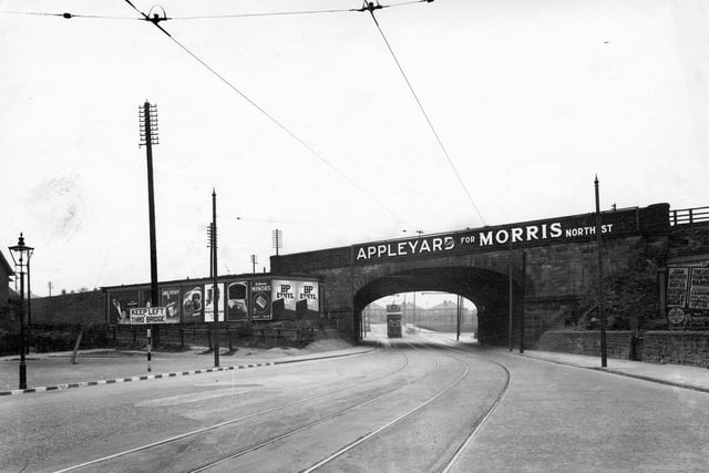 The railway bridge on Selby Road, looking from Osmondthorpe towards York Road. Tramlines are on the road and a tram is visible through the bridge.