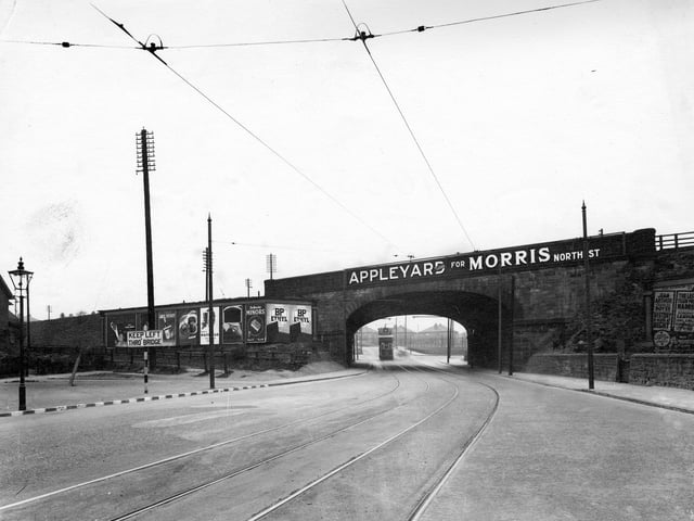 The railway bridge on Selby Road, looking from Osmondthorpe towards York Road. Tramlines are on the road and a tram is visible through the bridge.