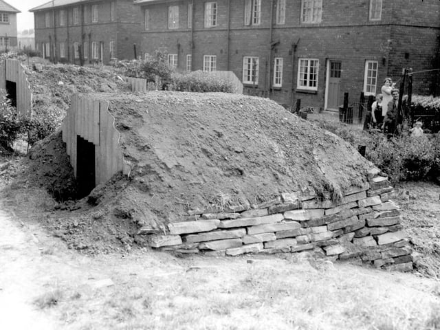 Anderson Shelter put up for no. 73 Wykebeck Avenue, reinforced by stone wall and earth. On the right a woman and children are watching the camera man.