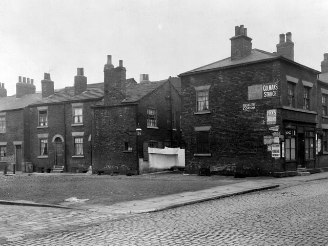 A small boy to left looks at the photographer on Czar Street. Terraced housing runs all the way along front walk. A shop is no 1 Front Walk owned by Jane Ann Burns. Sheets are hung outside a house on Bridge Road.