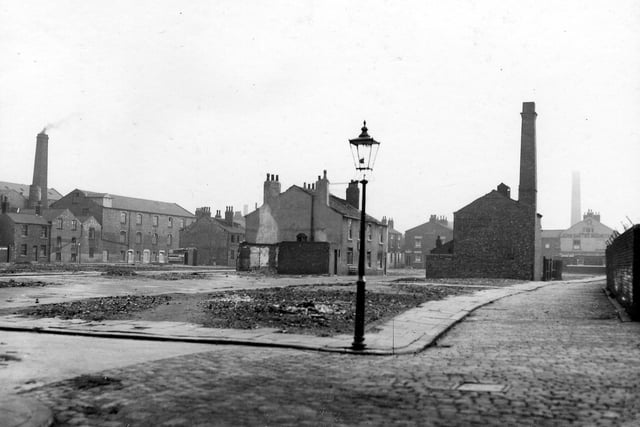 Camp Fields area after housing clearance, showing public houses and remaining mills. Street lamp in foreground. The Grove Inn can be seen at the bottom of Back Row, Bricklayers Arms in the middle of Middle Row
