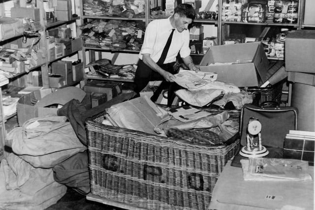 Post Office worker Dennis Alilson sorts through a mountain of damaged and undeliverable parcels in a Leeds storeroom.