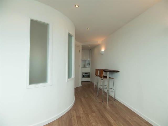 The kitchen dining area is shaped around a curved wall and leads to the living area.