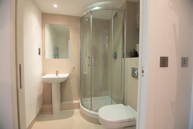 The bathroom is modern and has a shower and heated towel rack.