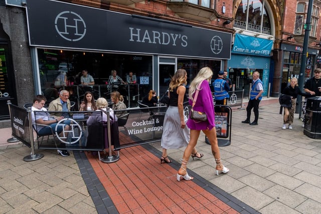 Customers who have pre-booked a table enjoying a drink outside Hardy's bar on New Briggate, Leeds.