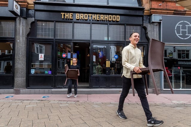 Olivia Ridgway, helps Alex Hutton, manager of The Brotherhood, New Briggate, Leeds, to carry out chairs in preparation for the reopening of their venue.
