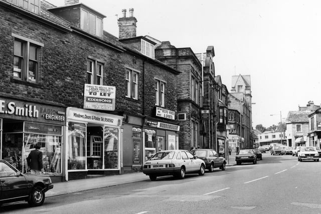 Lowtown. On the left is A.E. Smith, radio engineer, then Walkers & Wharfedale, windows, doors and patios. Row ends with Lowtown Mini-Market and off-licence. Following on is Pudsey Liberal Club then video film hire shop Video Value.