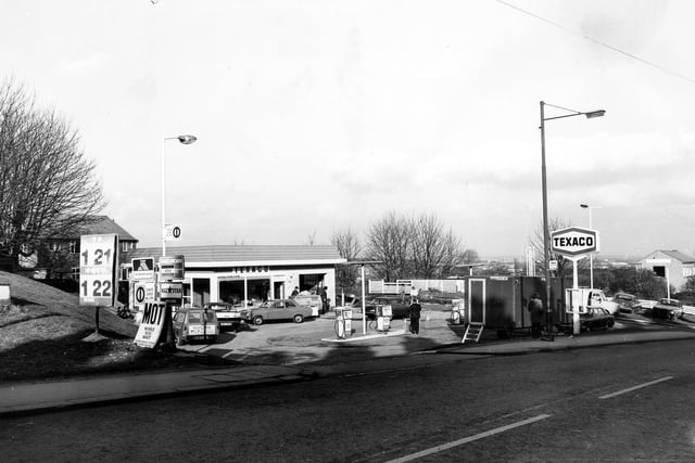 View of Wharrels petrol filling station on Lowtown. Petrol pumps can be seen and several cars and people are in view.