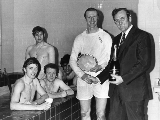 Don Revie presents Jack Charlton with a bottle of champagne and the Footballer of the Month trophy in the changing room after a match in 1972.