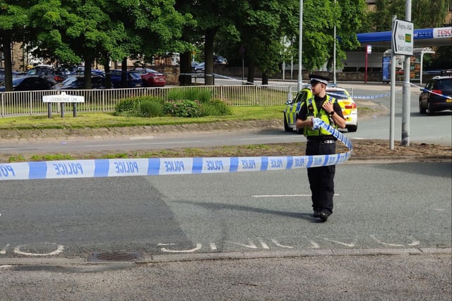An officer puts police tape near to the scene of the crash in Brighouse