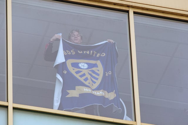 Gianni Alioski holds a Leeds flag aloft as he watches fans celebrate outside Elland Road.