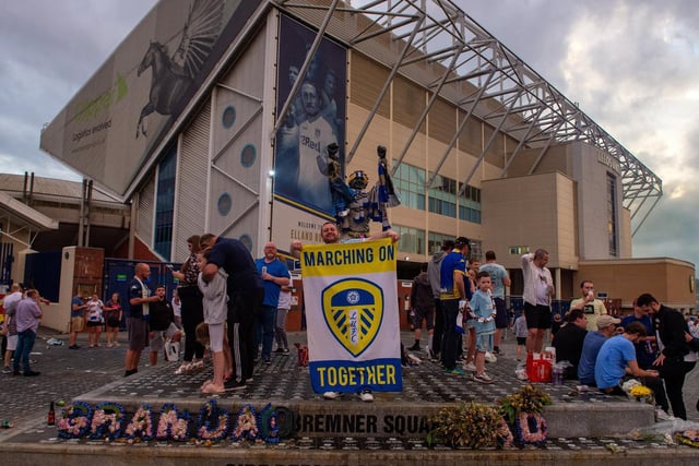 A fan poses with a Leeds United flag in front of the Billy Bremner statue at Elland Road.