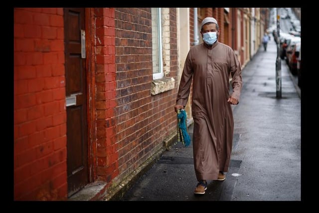 A man wears a face mask as he makes his way to the local mosque in Blackburn