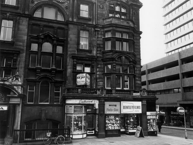 Albion Place with the YMCA building on the left. Eastwood tobacconists and Bentley Films Ltd. occupy shops on the ground floor. To the right is the junction with Albion Street and the tower block West Riding House.