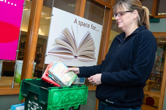 Aileen Smedley, library officer at St Anne's library, demonstrates how to return used books- by putting them in a designated box. The books will then be shelved no less than two hours later.