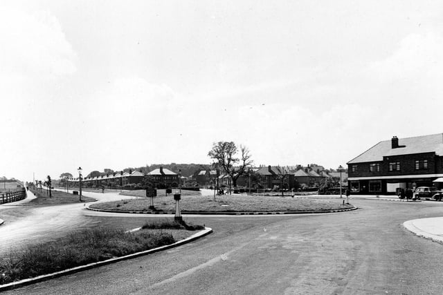 View looking south-east along Station Road towards the Ring Road and Whitkirk in July 1945. A roundabout is central. Bollards, a 'keep left' sign, lamposts and a car are visible.