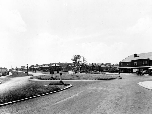 View looking south-east along Station Road towards the Ring Road and Whitkirk in July 1945. A roundabout is central. Bollards, a 'keep left' sign, lamposts and a car are visible.